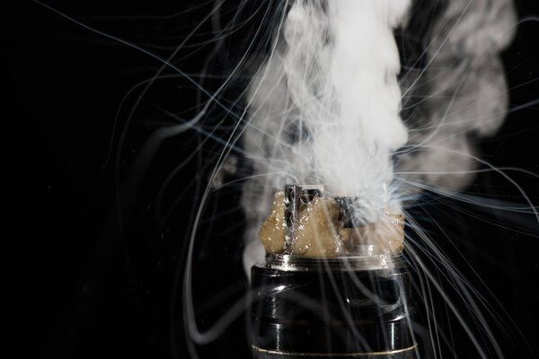 Activating electronic cigarette with clouds of smoke on dark background