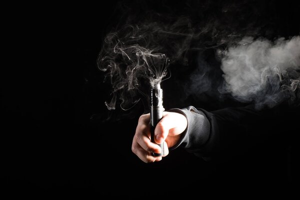 Cropped view of male hand activating electronic cigarette on black background