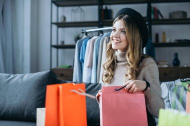 alışveriş torbaları ile oturan gülümseyen moda blogger