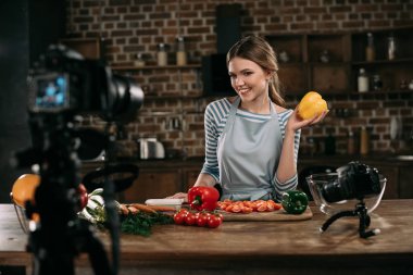 Sarı dolmalık biber elinde tutan genç gıda blogger gülümseyen