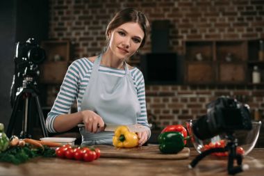 Bulgar biber kesme ve kameraya bakarak genç gıda blogger