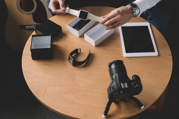 обрезанное изображение технологического блогера, держащего в руках новые умные часы
