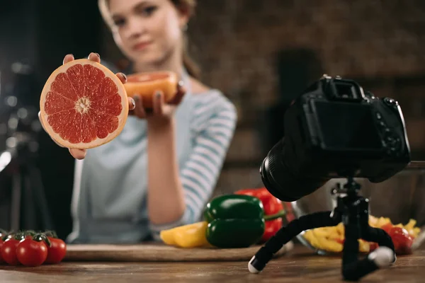 young food blogger showing half of grapefruit to camera