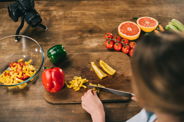 overhead view of female food blogger cutting bell peppers