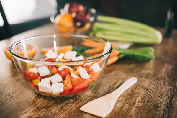 стеклянная чаша с салатом и деревянной лопаткой на столе

