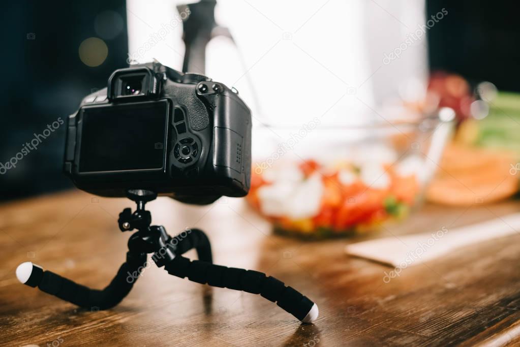 digital camera on table with salad on blurred background