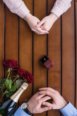 aralarında nikah yüzüğü ile masada oturan çift kırpılmış