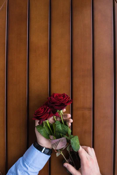 Imagem Cortada Homem Segurando Buquê Rosas Vermelhas Mesa — Fotografia de Stock