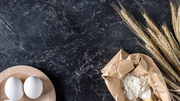 暗い大理石のテーブルの上の未加工卵 小麦粉 小麦の配置平面図 — ストック写真