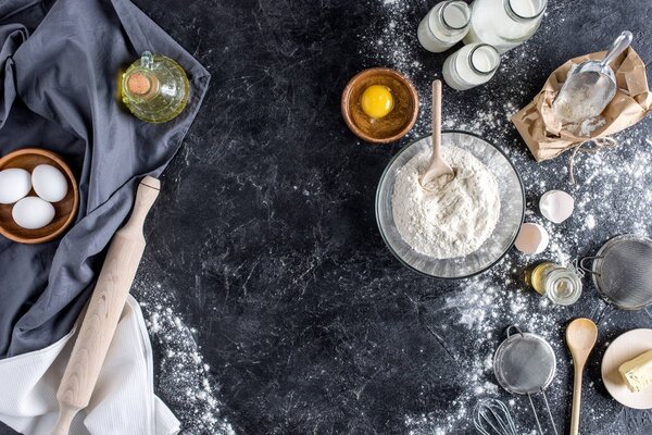 top view of arranged kitchenware and ingredients for bread baking on dark marble surface