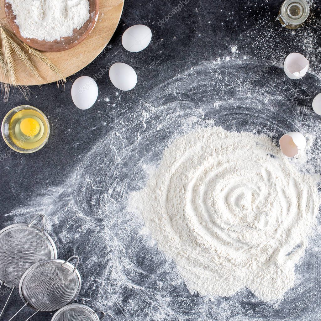 top view of arranged sieves, raw eggs and flour on dark tabletop