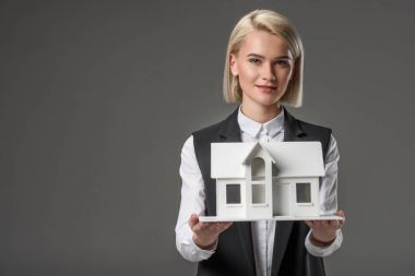 portrait of young real estate agent with house model isolated on grey clipart