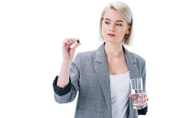 woman holding glass of water and activated carbon tablet, isolated on white