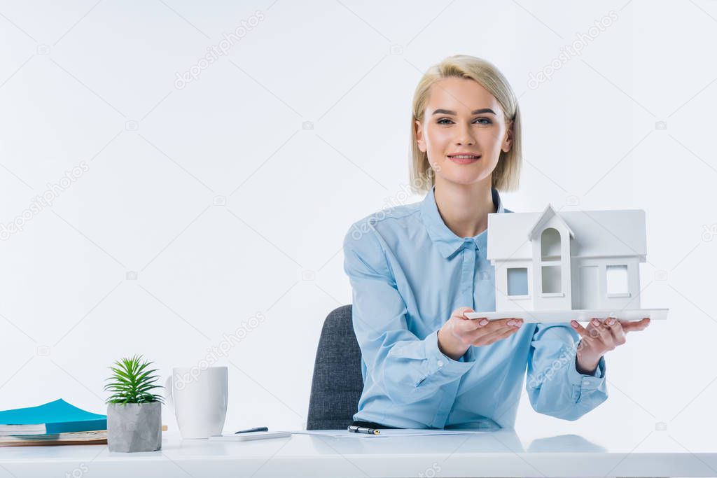 portrait of real estate agent showing house model at workplace