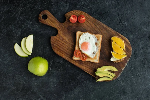 まな板の上のトーストと目玉焼き 朝食のミニトマトのトップ ビュー  — 無料ストックフォト
