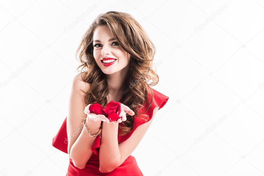 smiling attractive girl showing red rose petals in hands isolated on white