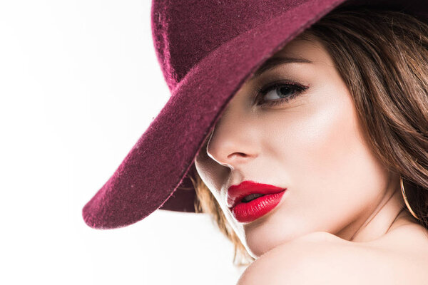снимок привлекательной девушки в бургундской шляпе, смотрящей на камеру в белом
