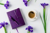 top view of cup of coffee and scattered iris flowers on white table