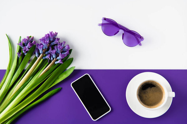 top view of bouquet of purple hyacinth flowers and smartphone on table