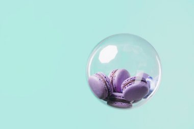 lezzetli mor macarons turkuaz arka plan üzerinde yüzen cam top