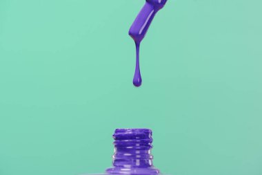 nail polish pouring down into bottle isolated on turquoise clipart