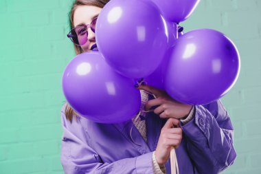 Mor balon saklanıyor güneş gözlüklü genç kadın