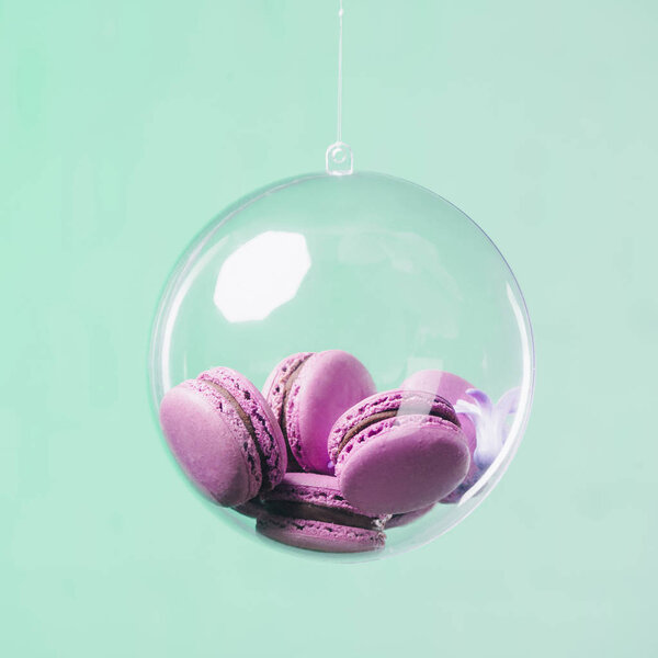 macarons in glass ball hanging on turquoise background