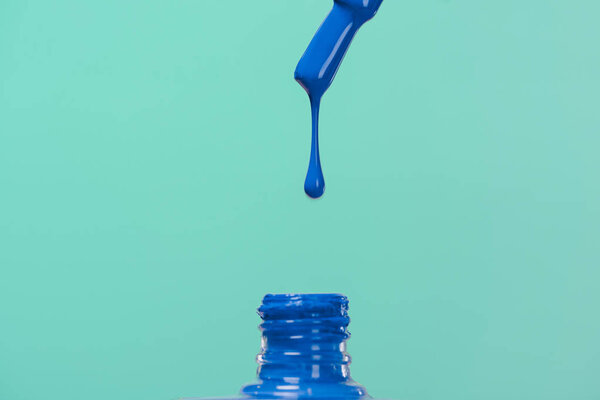 nail polish pouring down into bottle isolated on blue
