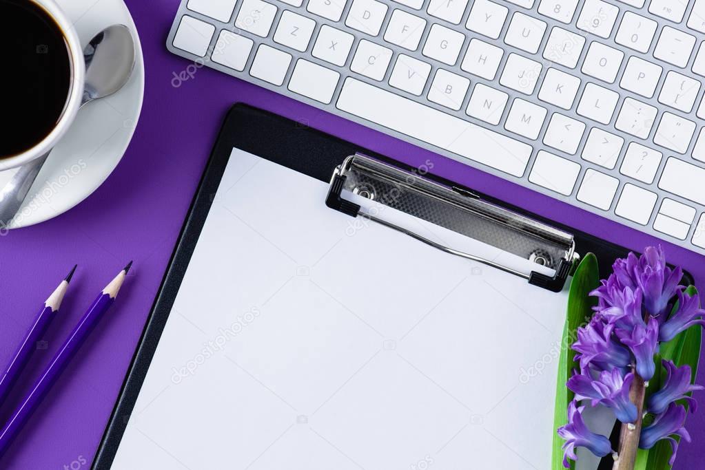 top view of workspace with blank clipboard and computer keyboard