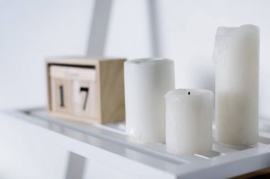 three white candles on white shelf clipart