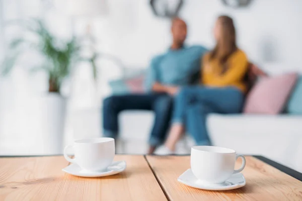 Multicultural Couple Holding Hands Sofa Cups Coffee Foreground — Stock Photo, Image