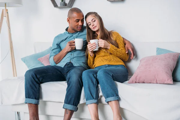 多文化情侣坐在沙发上喝咖啡 — 免费的图库照片