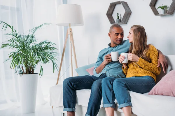 Multikulturelles Paar Sitzt Auf Sofa Mit Kaffee — Stockfoto