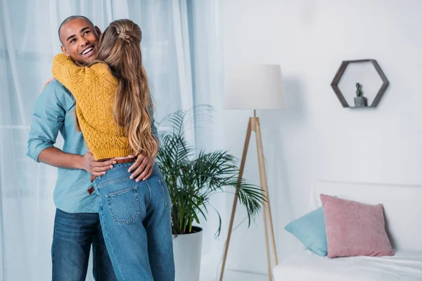 Smiling Multicultural Couple Hugging Room — Free Stock Photo