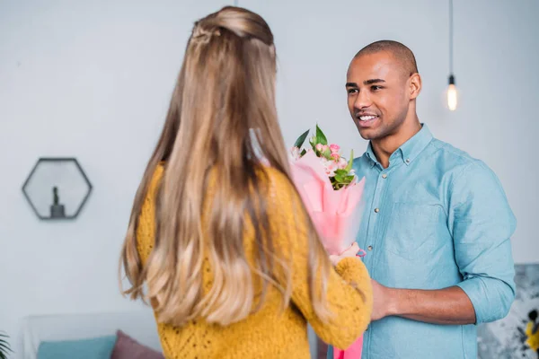 african american boyfriend presenting bouquet to girlfriend