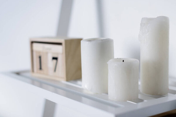 three white candles on white shelf