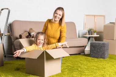 happy mother and daughter smiling at camera while having fun during relocation clipart