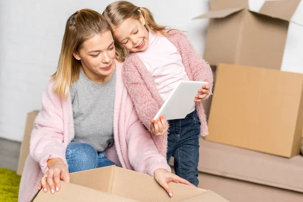 Happy Mother Daughter Using Digital Tablet While Packing Cardboard Boxes — Stock Photo, Image