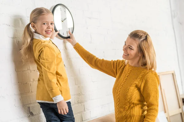 Bella Madre Felice Figlia Appeso Orologio Sul Muro Durante Trasferimento — Foto Stock