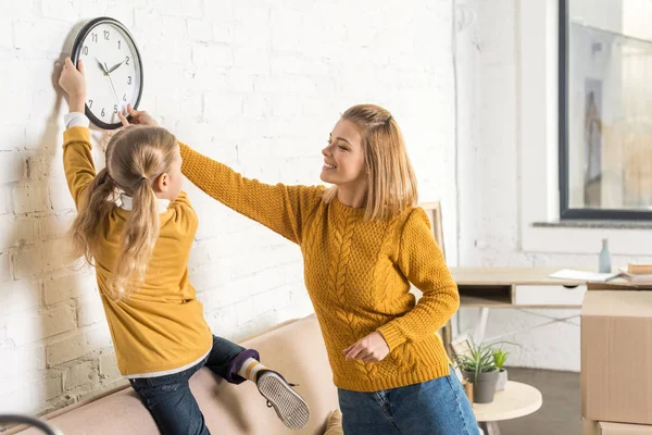 Felice Madre Figlia Appeso Orologio Sul Muro Durante Trasferimento — Foto Stock