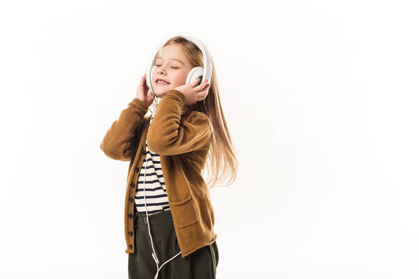 joyful little child listening music with headphones isolated on white