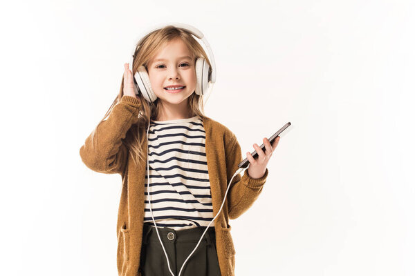 adorable little child listening music with headphones and smartphone isolated on white