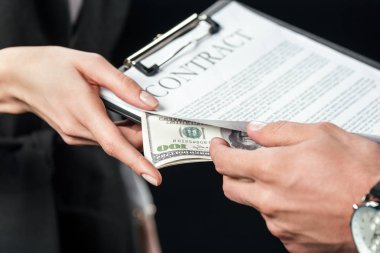 cropped view of businesspeople holding contract and bribe, isolated on black clipart