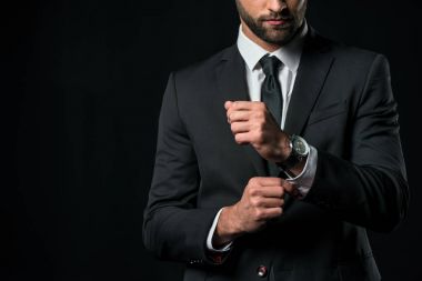 cropped view of businessman in jacket with wristwatch, isolated on black