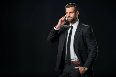 smartphone, siyahta izole konuşurken ceketli yakışıklı işadamı