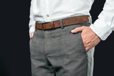 cropped view of businessman with hands in pockets, isolated on black clipart