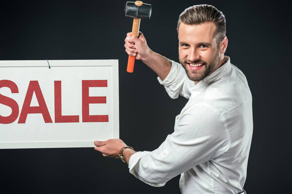 handsome man with hammer and sale sign, isolated on black