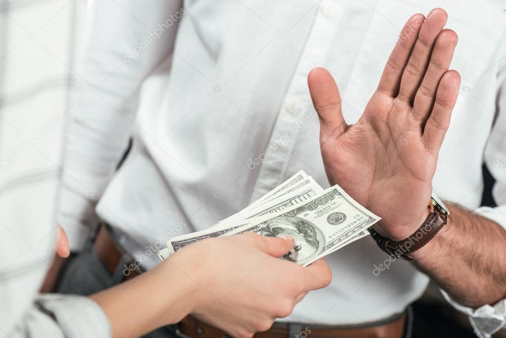 cropped view of businessman refusing to take bribe from partner, isolated on black