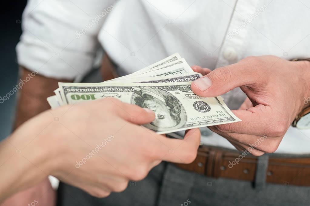 cropped view of businesspeople holding dollar banknotes, isolated on black