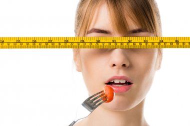 genç kadın teyp ölçme ile kiraz domates yeme önünde gözleri beyaz izole.